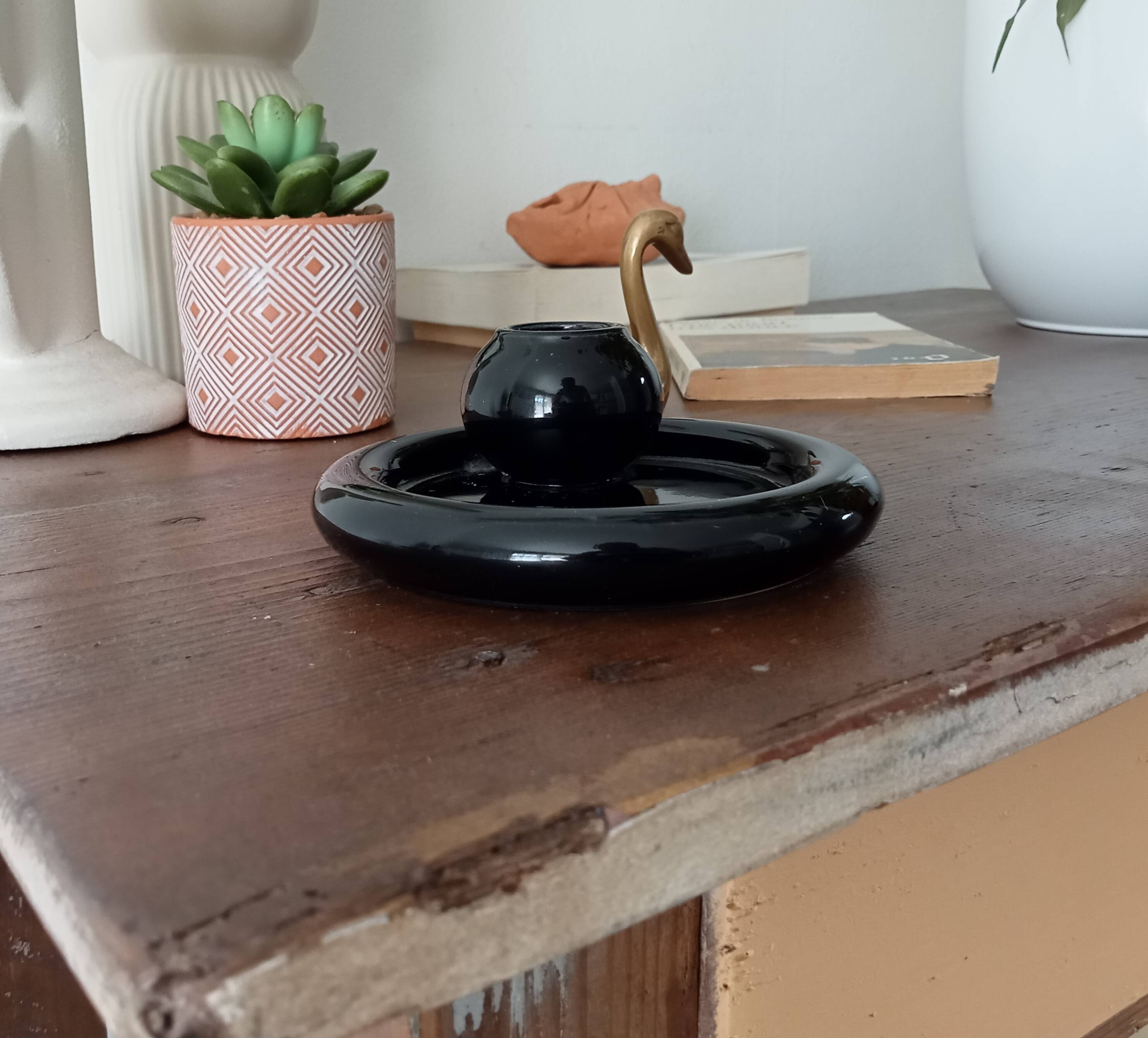 Vintage black ceramic candle holder on a bowl