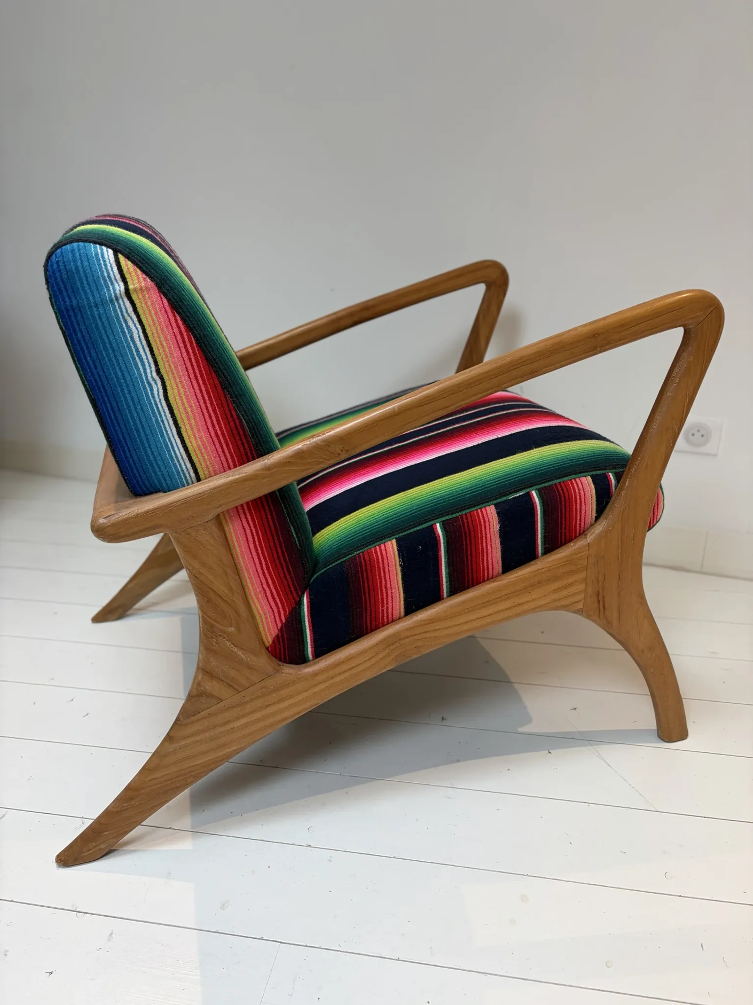 Scandinavian-style armchair in curved wood and colourful striped fabric.