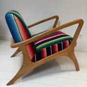 Scandinavian-style armchair in curved wood and colourful striped fabric.