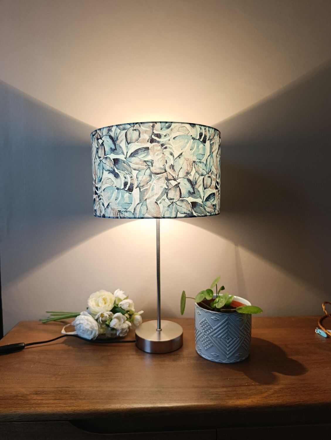Table lamp with chrome stem, tropical plant shade.