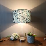 Table lamp with chrome stem, tropical plant shade.