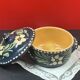 Small covered terracotta pot enamelled savoie or alsace flowers on a blue background