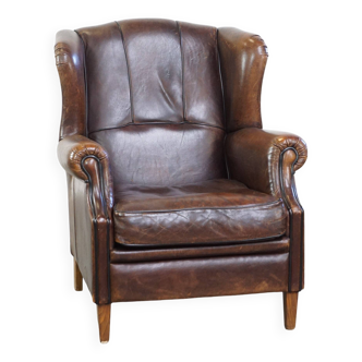 Fauteuil à oreilles en peau de mouton et finition soignée avec passepoil noir
