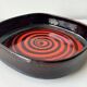 Large decorative ceramic catchall with red and black spiral pattern.