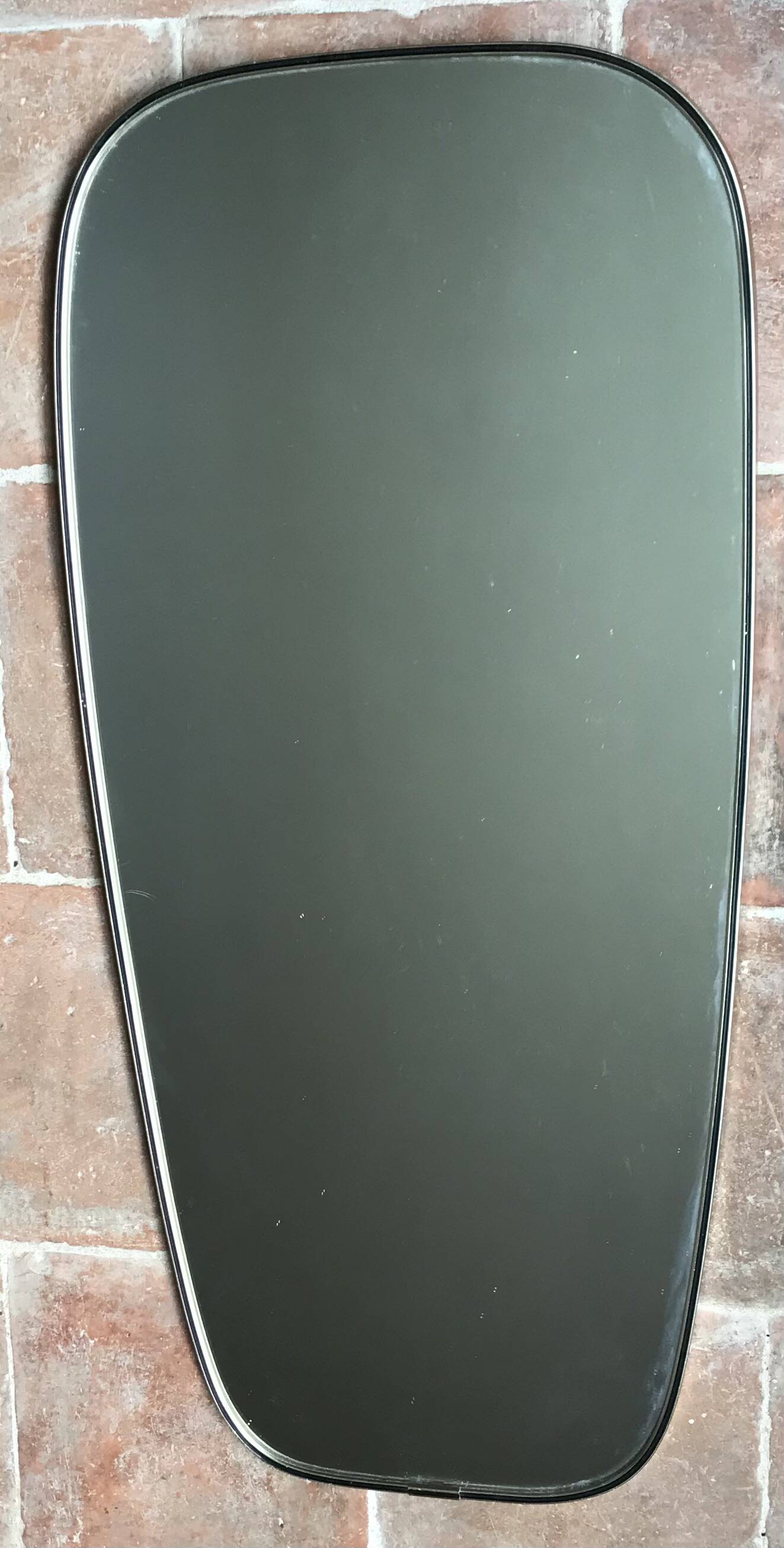 Vintage 1960 free-form mirror known as a retro mirror with a gold and black metal trim.