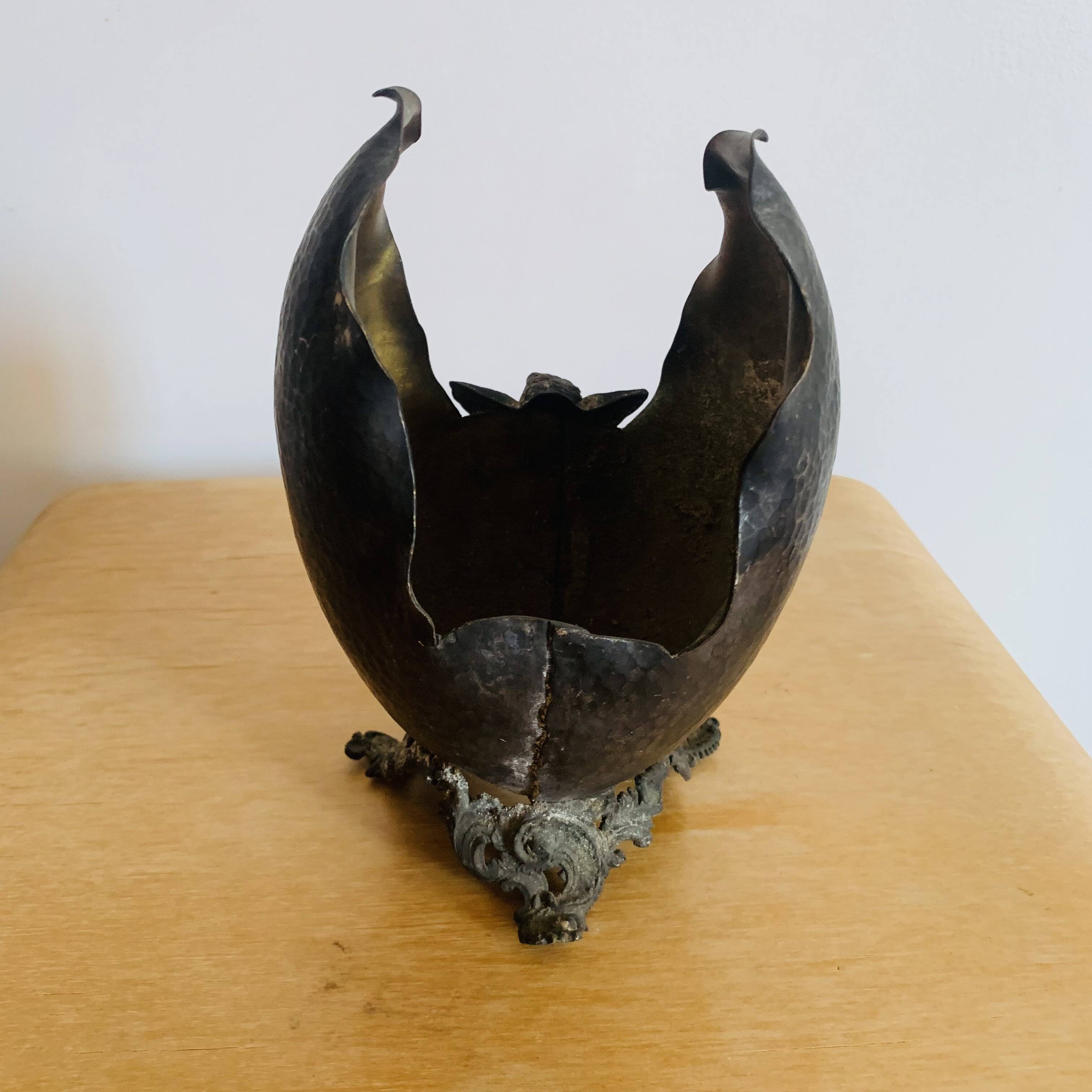 Antique decorative cup in hammered metal with putto design.