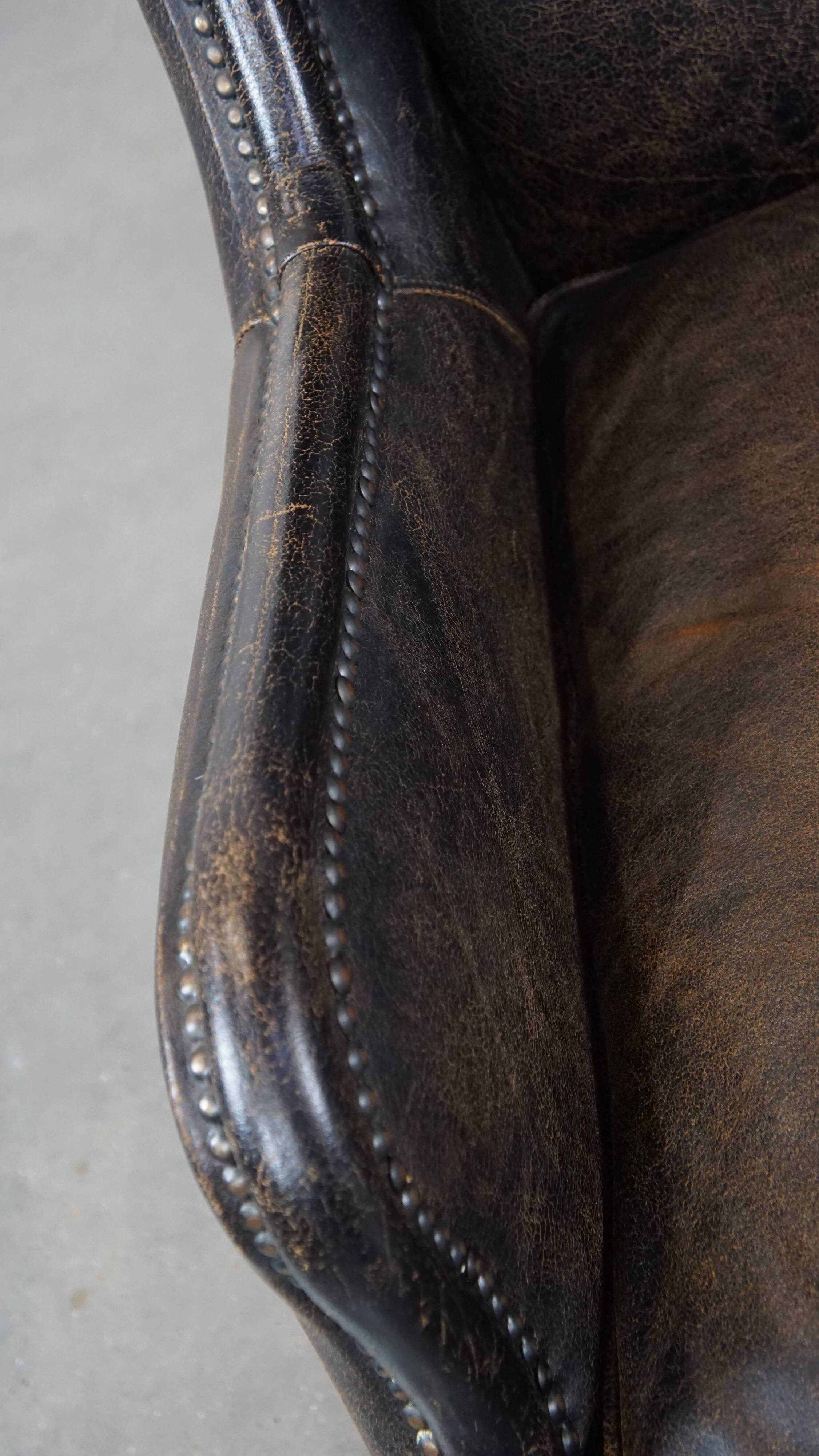 Black cow leather armchair finished with decorative nails, industrial style