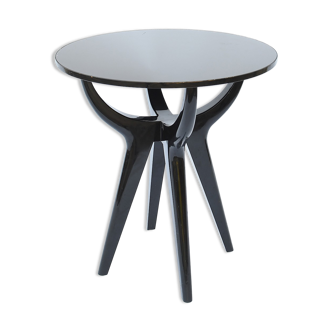 Circular pedestal table with black lacquered quadripod base and glass top
