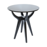 Circular pedestal table with black lacquered quadripod base and glass top