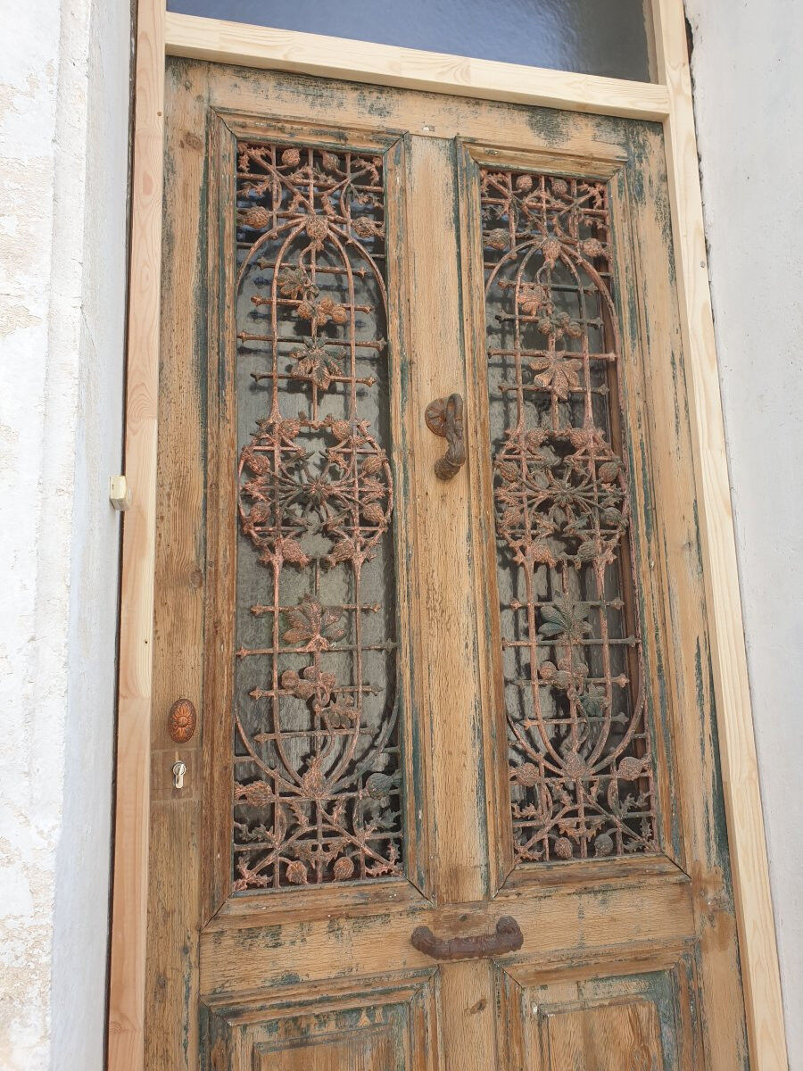 Front door of a house or building in the city centre, with a dolphin door knocker and frame + transom.