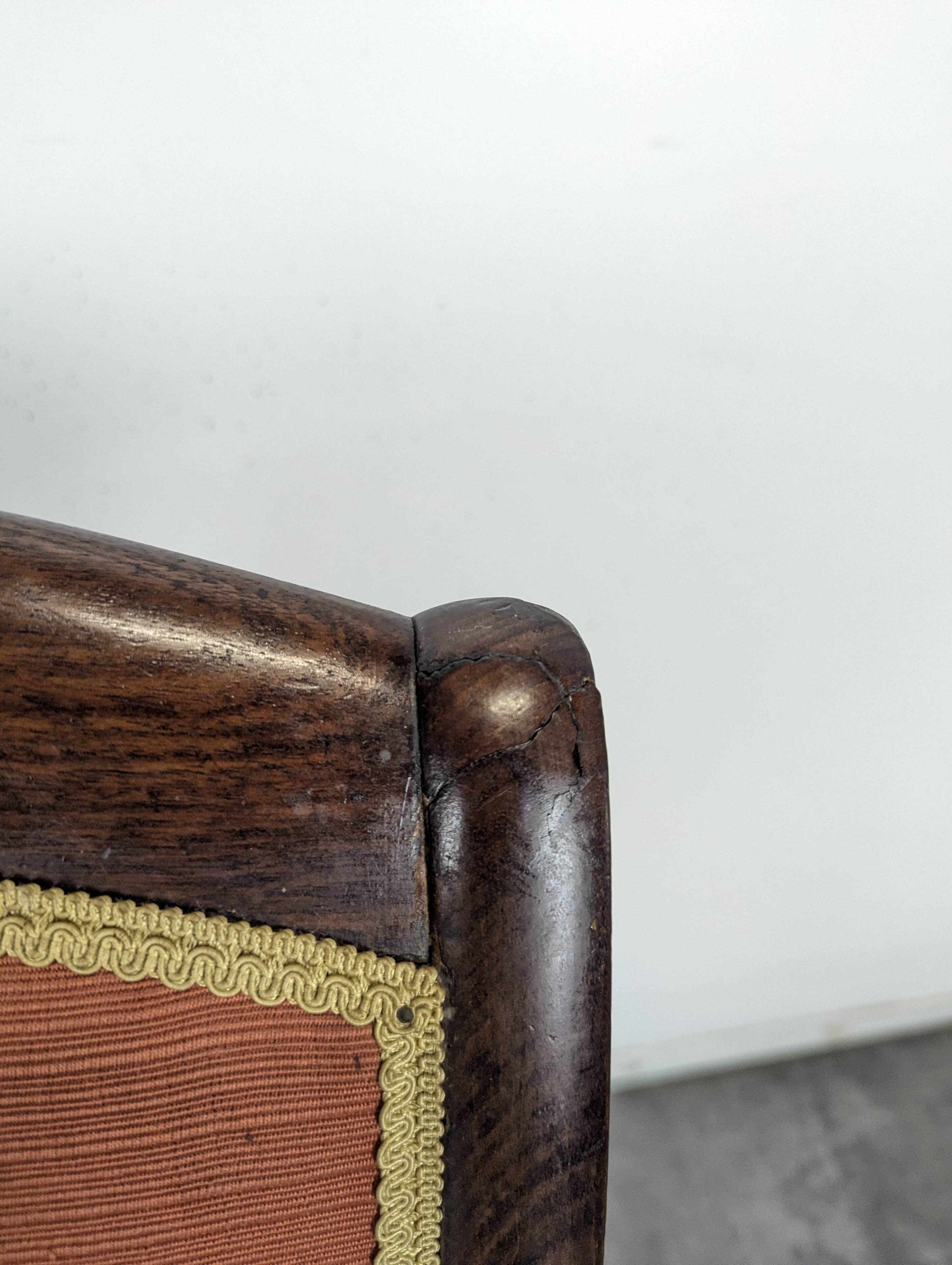 Restoration armchair in mahogany with cross arms and orange fabric.