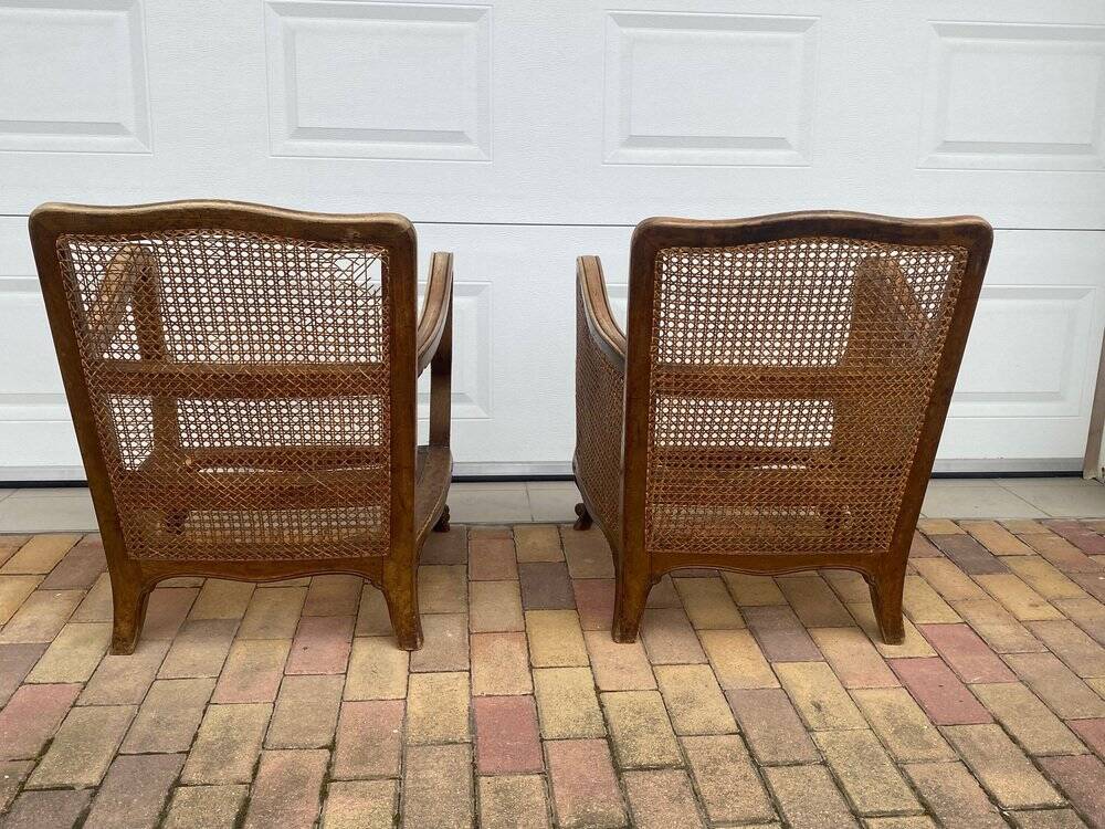 Pair of 1920s brown armchairs in carved wood and fabric, with caning detail.