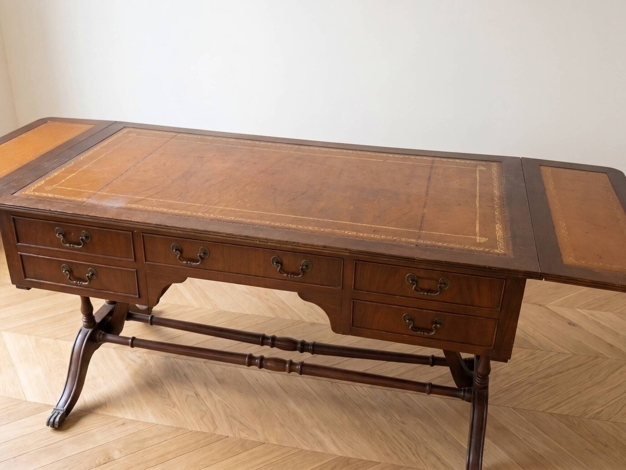 Antique wooden desk with a faux leather top and extensions.