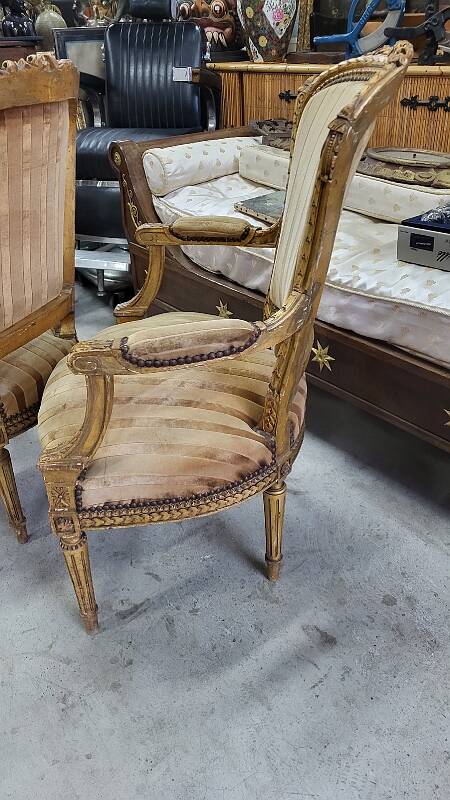A pair of gilded wooden armchairs in the Louis XVI style.