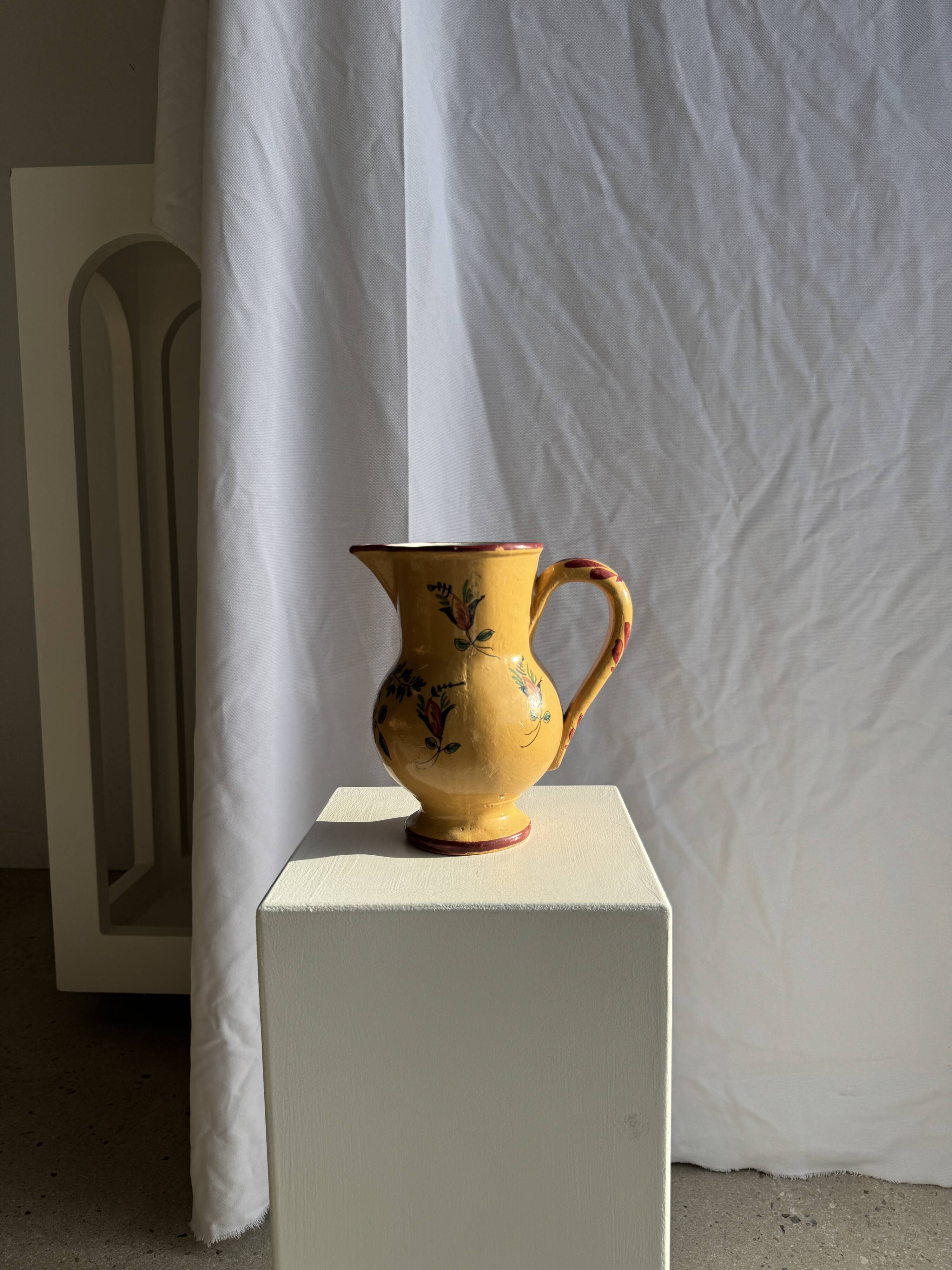 Large antique handmade ochre yellow jug with a pink flower pattern.