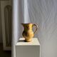 Large antique handmade ochre yellow jug with a pink flower pattern.