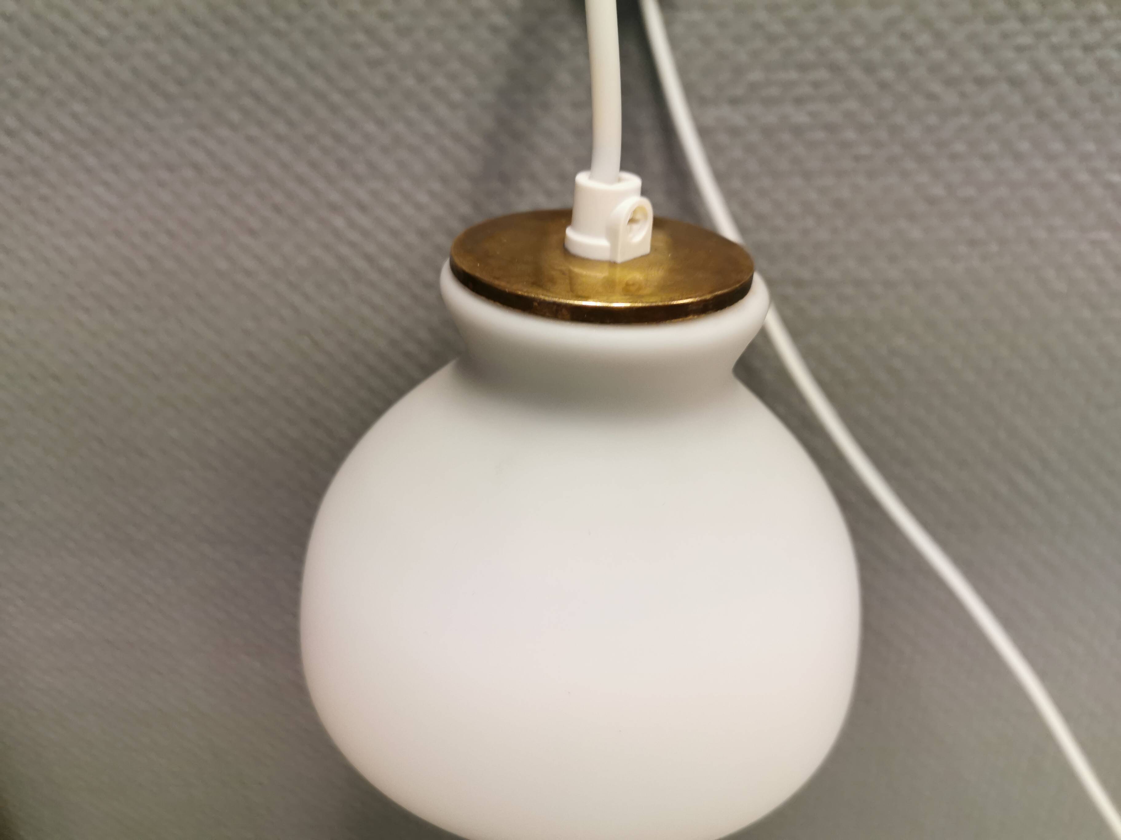 Milky white Holmegaard wall lamp with glass shade and a brass detail on top. Wooden wall bracket