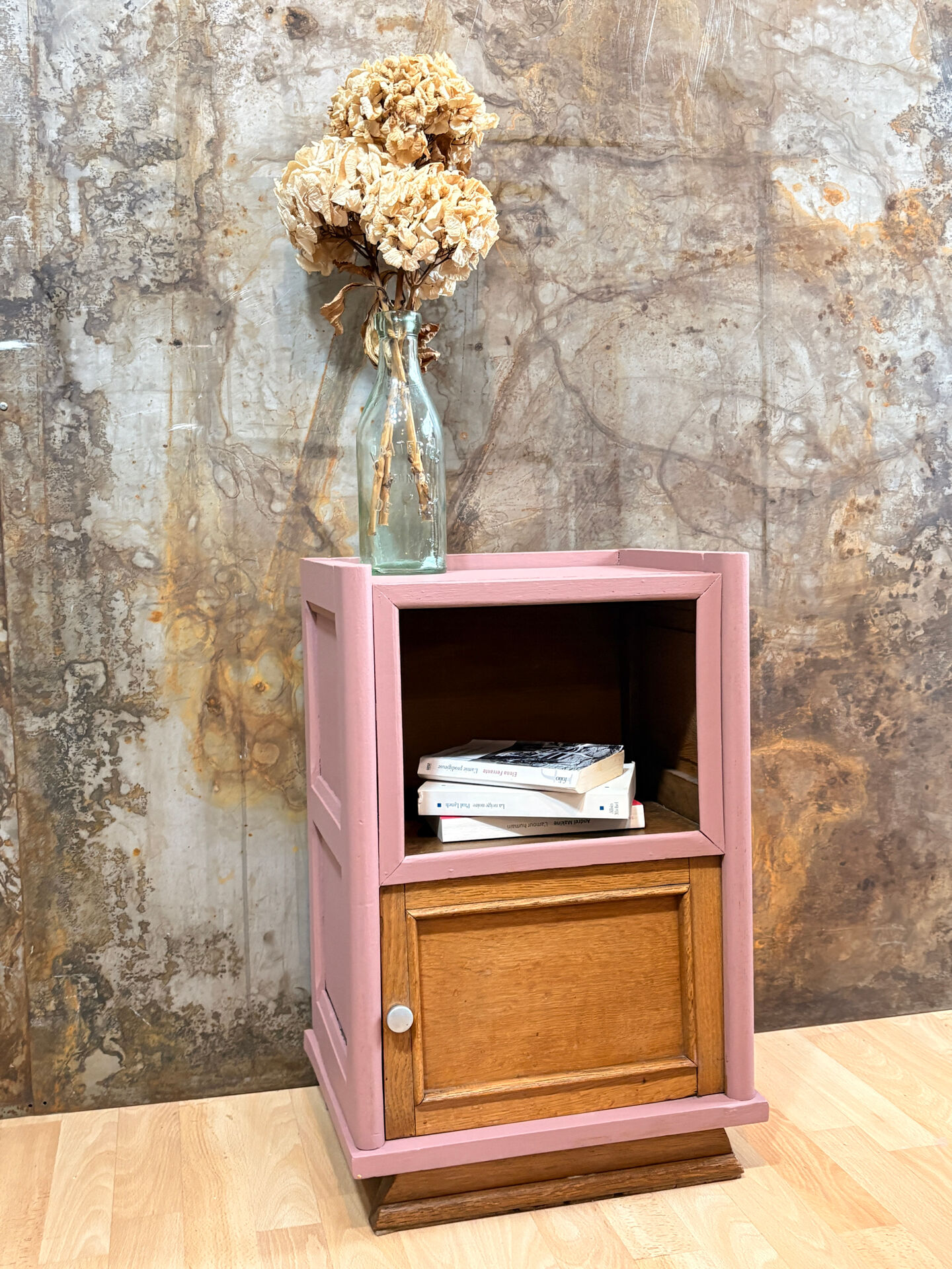Pink bedside table with haberdashery and raw wood.