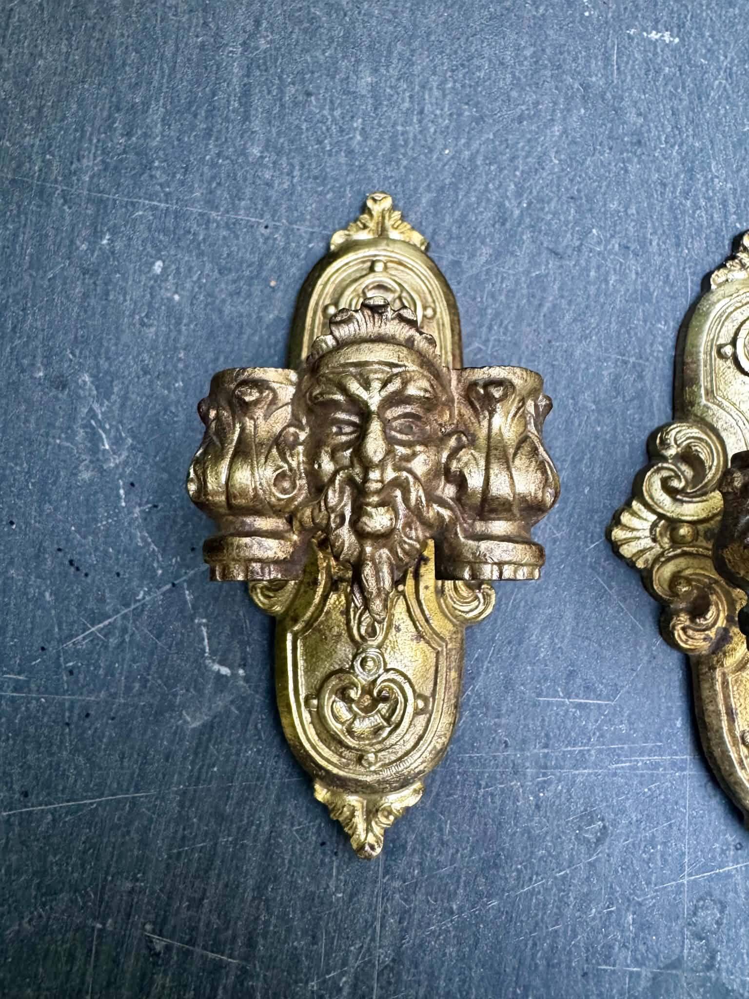 Pair of bronze wall sconces with mask, signed L. Pinet, Art Nouveau period.