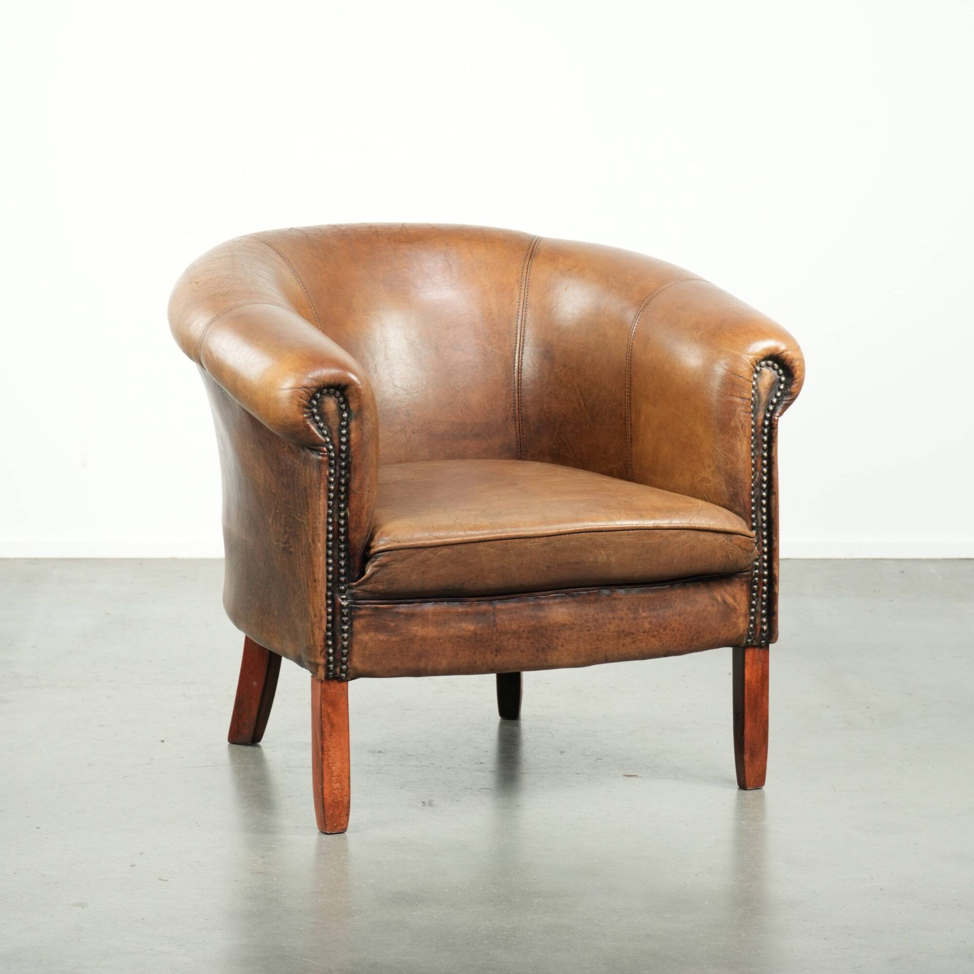 Sheepskin club armchair in a brown colour finished with decorative nails