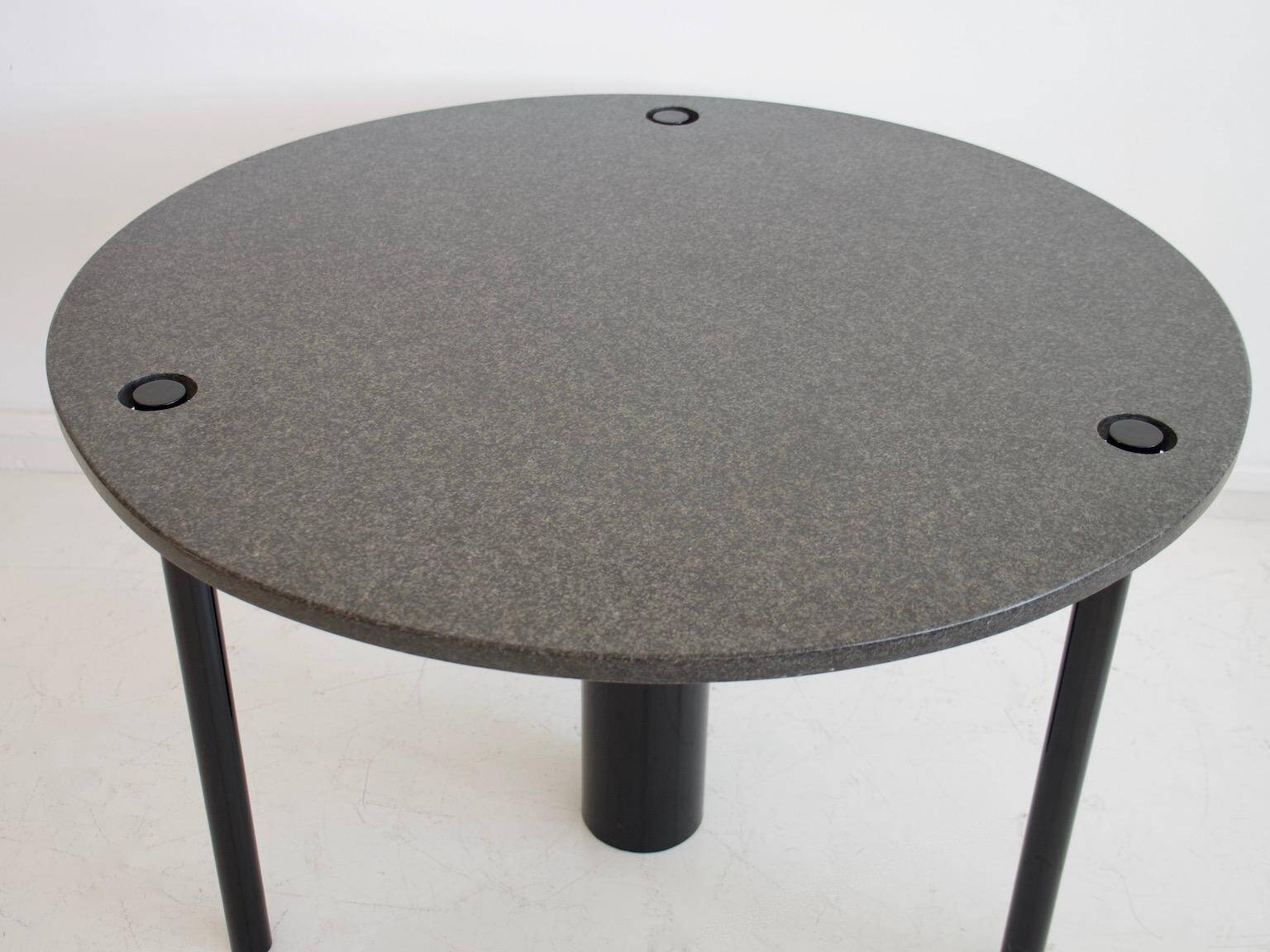 Round dining table in black lacquered metal with a granite top.