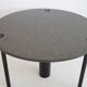 Round dining table in black lacquered metal with a granite top.