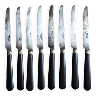 A set of 8 black wooden handled knives.