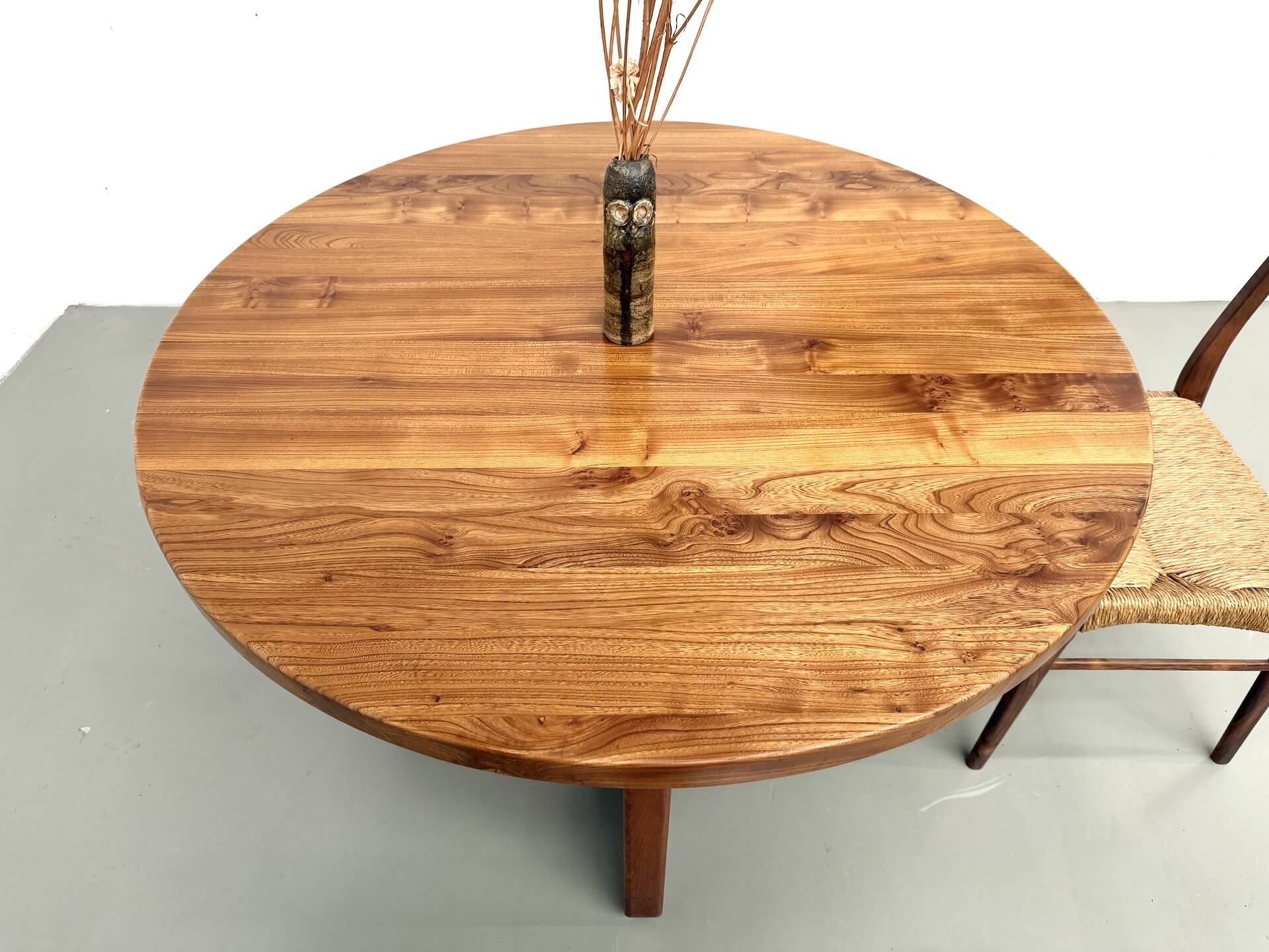 Modernist round table in solid elm, crossed legs.