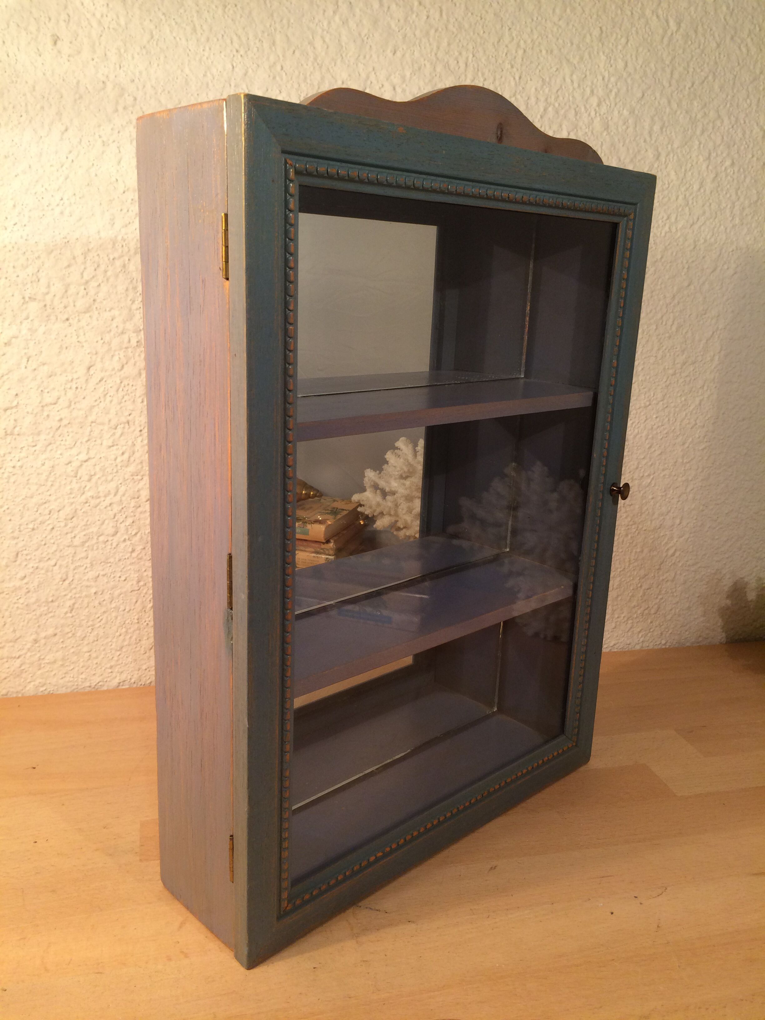 Display shelf with miniature blue wood and mirrors