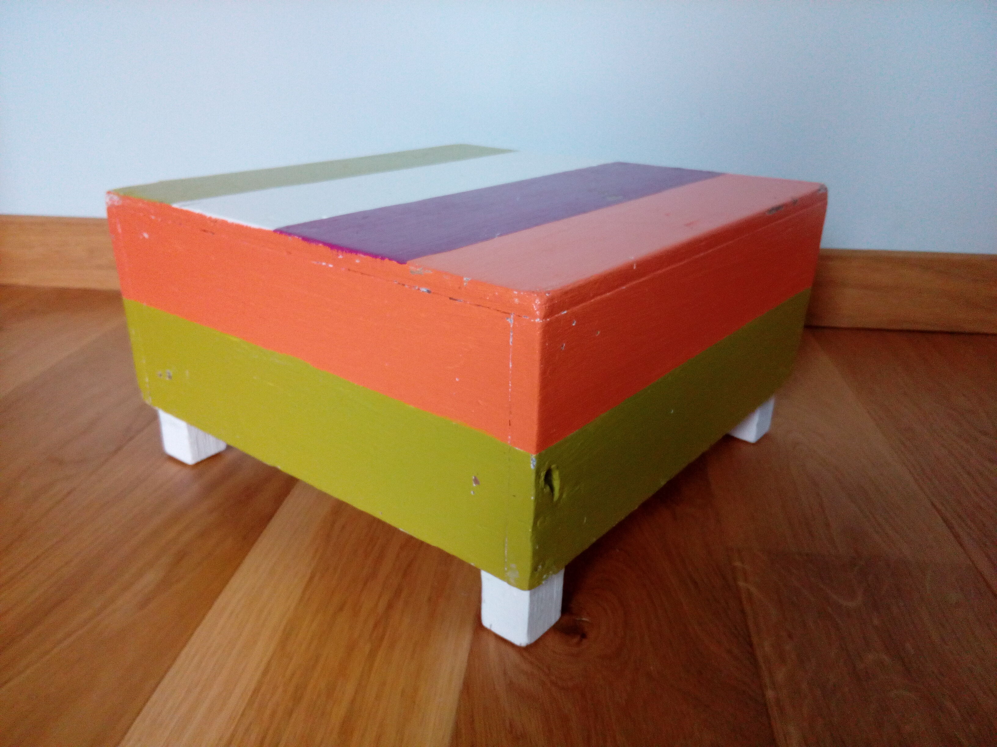 Low wooden stool painted in bright colours