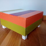 Low wooden stool painted in bright colours
