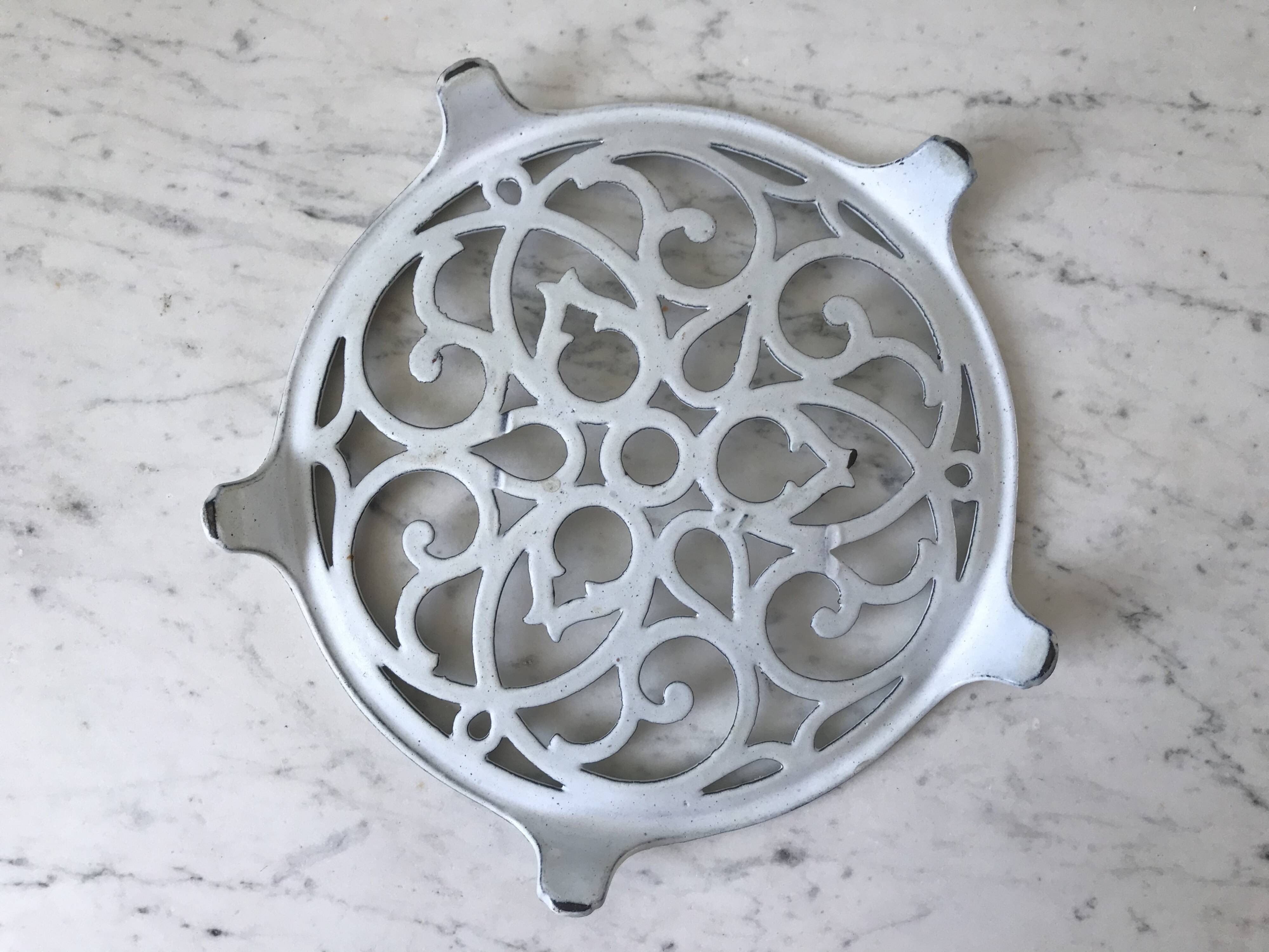 Vintage white cast iron trivet from the early 20th century