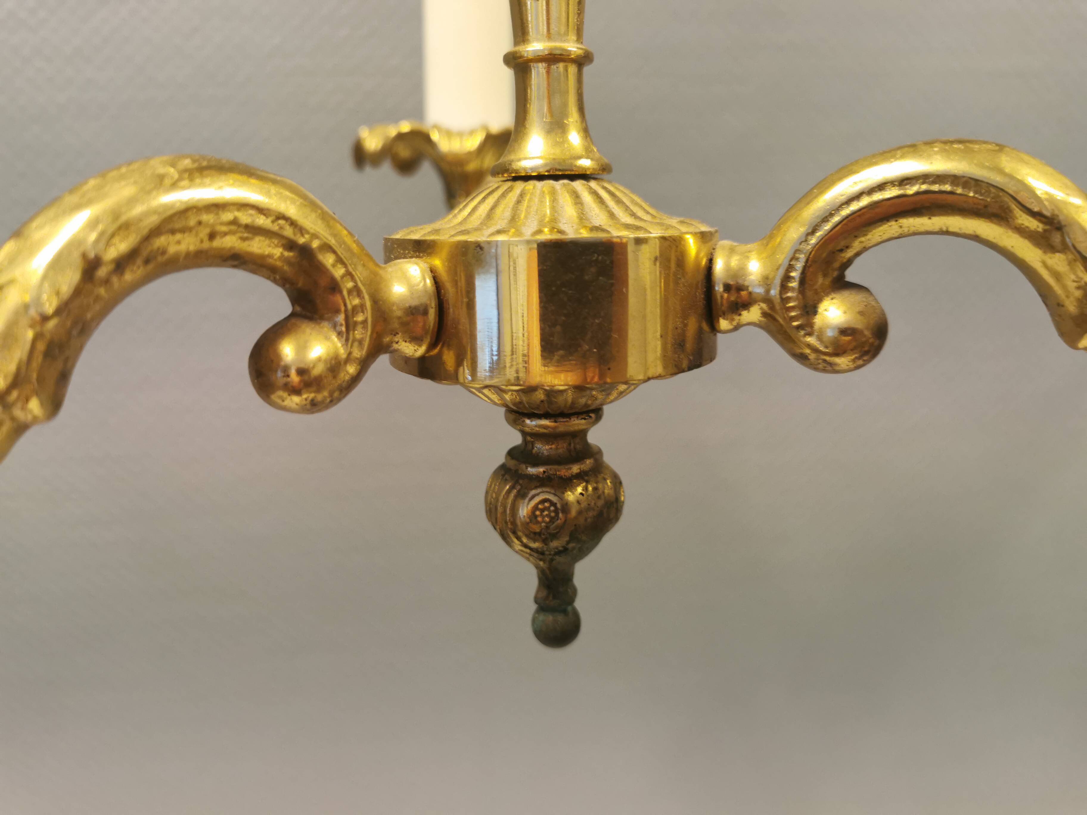 Older brass alloy chandelier with three light sources.