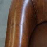 Subtle, neat sheepskin leather club armchair with a fixed seat cushion in a deep, dark cognac color