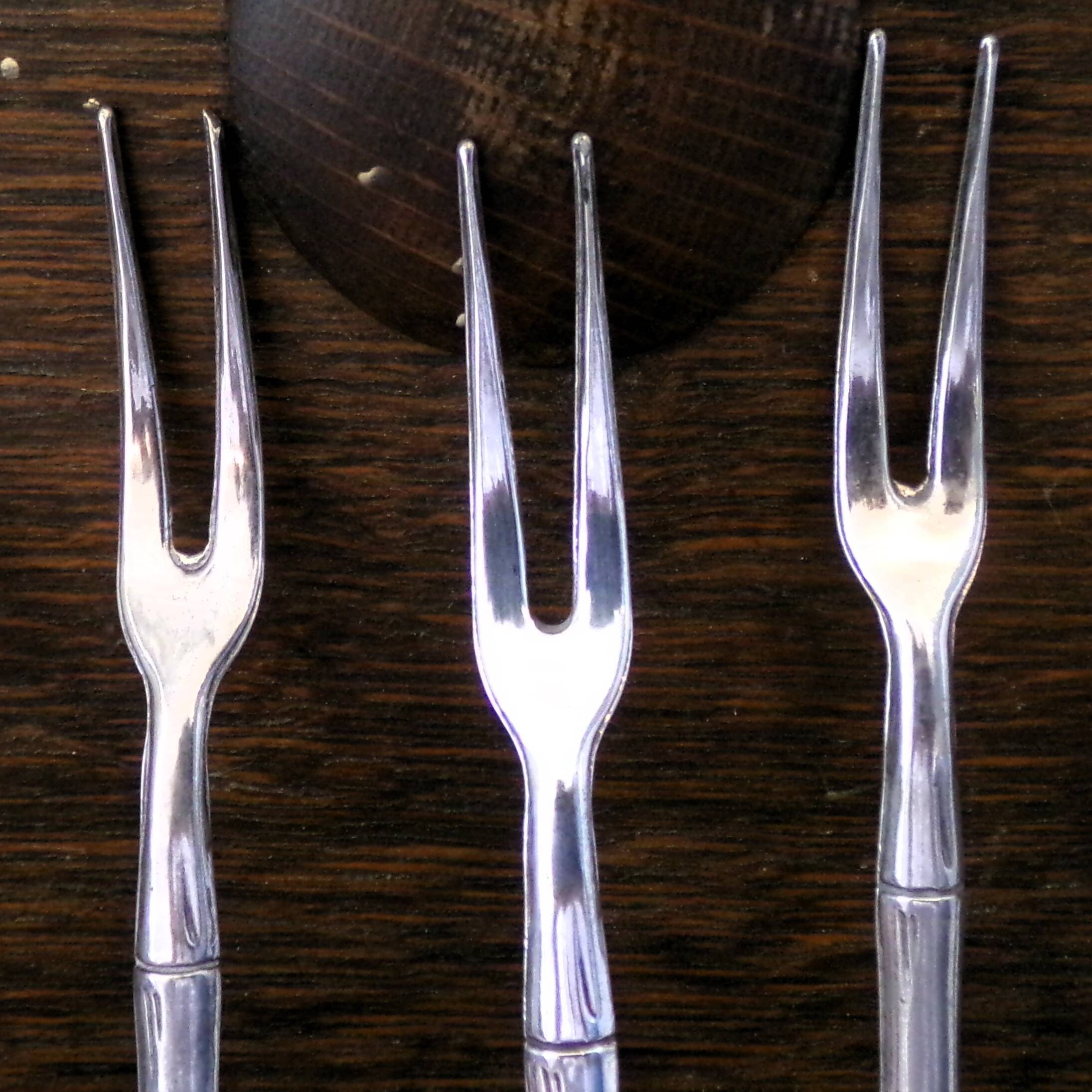 Five silver-plated metal appetizer forks with bamboo-style handles