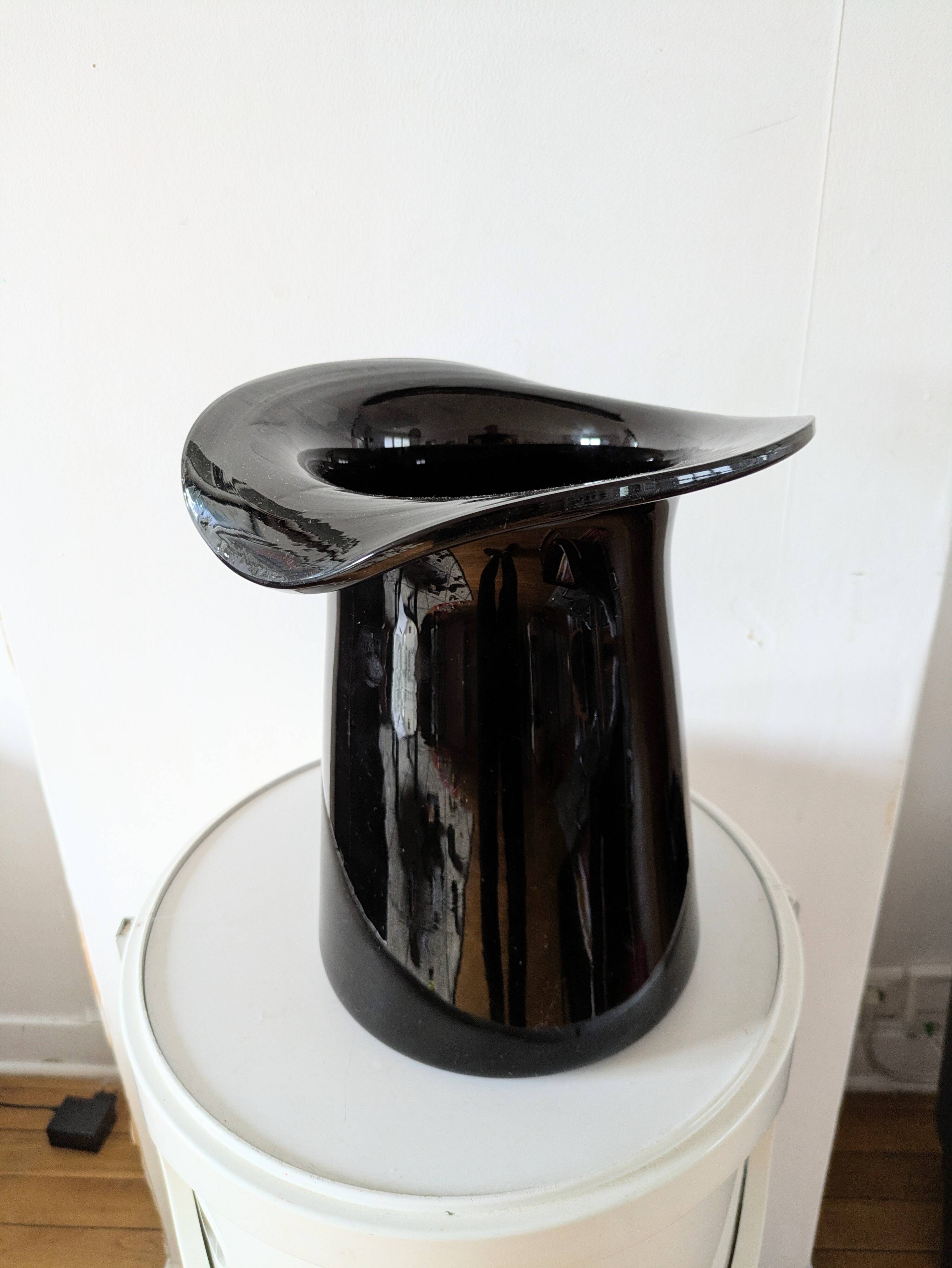 Large black glass vase topped with a 70s hat