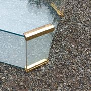 1970s designer coffee table in glass, plexiglass, and gold metal.