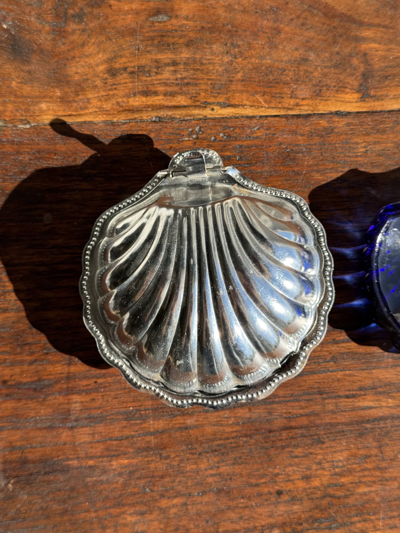 Vintage silver-plated shell butter dish with blue bowl.
