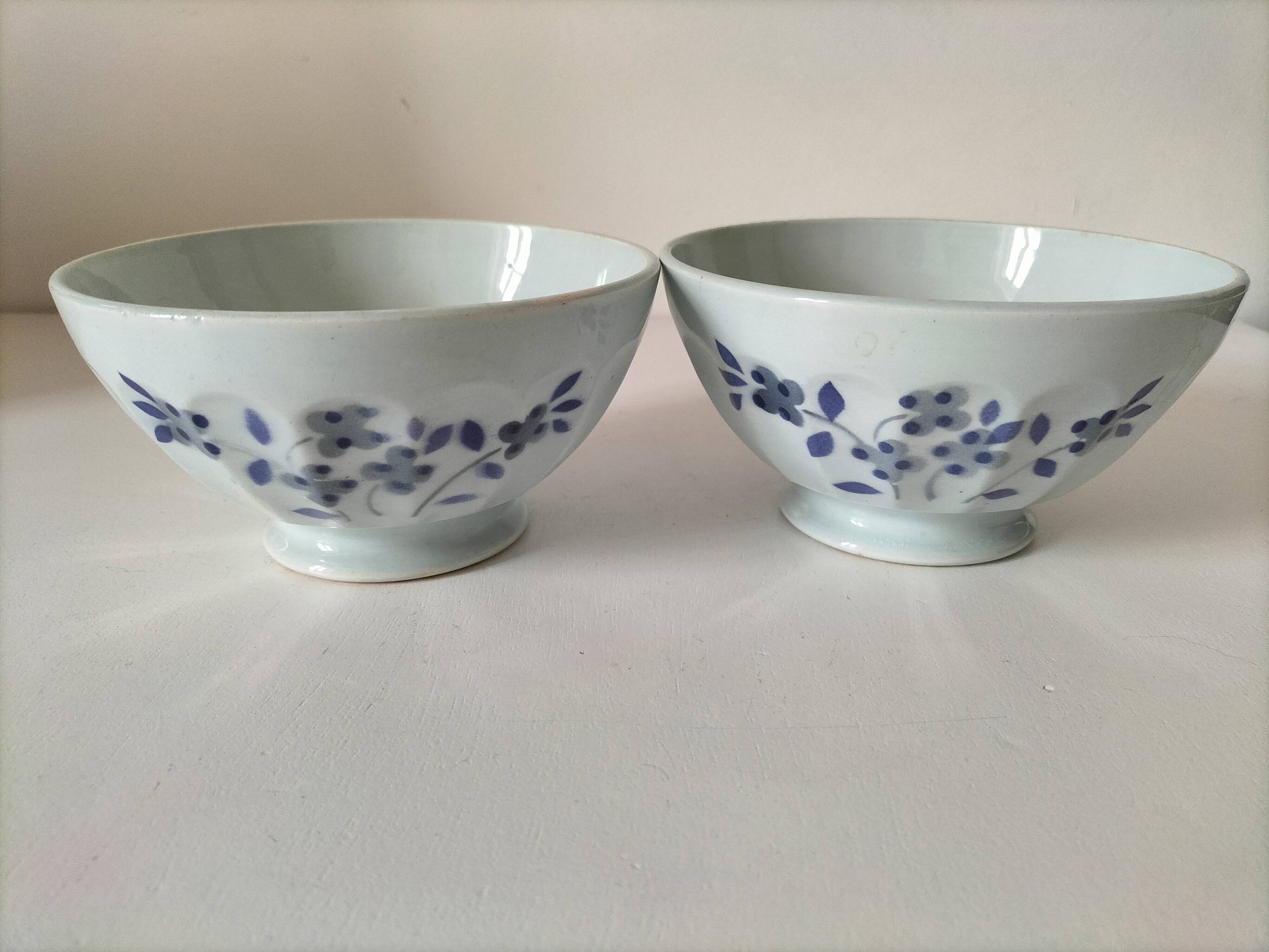Two vintage farm bowls on a pale blue pedestal with floral decoration.