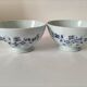 Two vintage farm bowls on a pale blue pedestal with floral decoration.