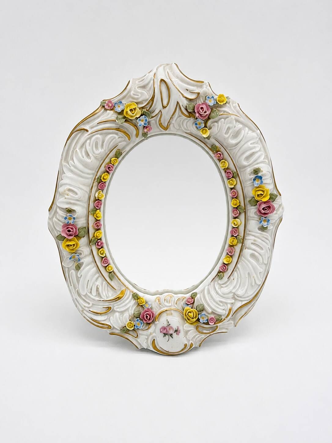Antique porcelain mirror from Dresden with relief flowers and rococo decoration.