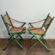 Paire de chaises safari pliantes façon faux-bambou patiné, dossiers et assises cannées et repose-bras en cuir