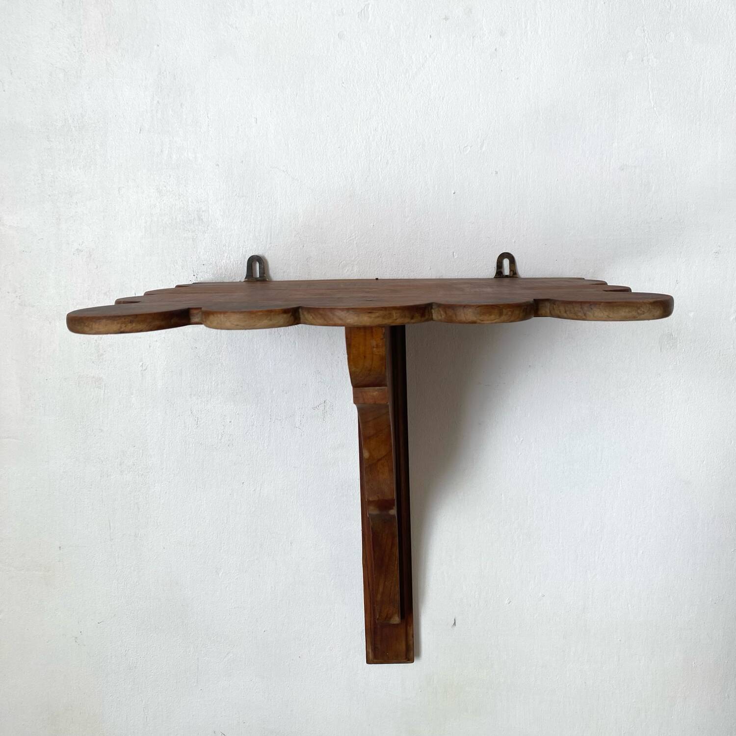 Antique wall shelf with a scalloped edge.