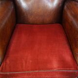 Sheep leather wingback chair with a red corduroy seat cushion and patina
