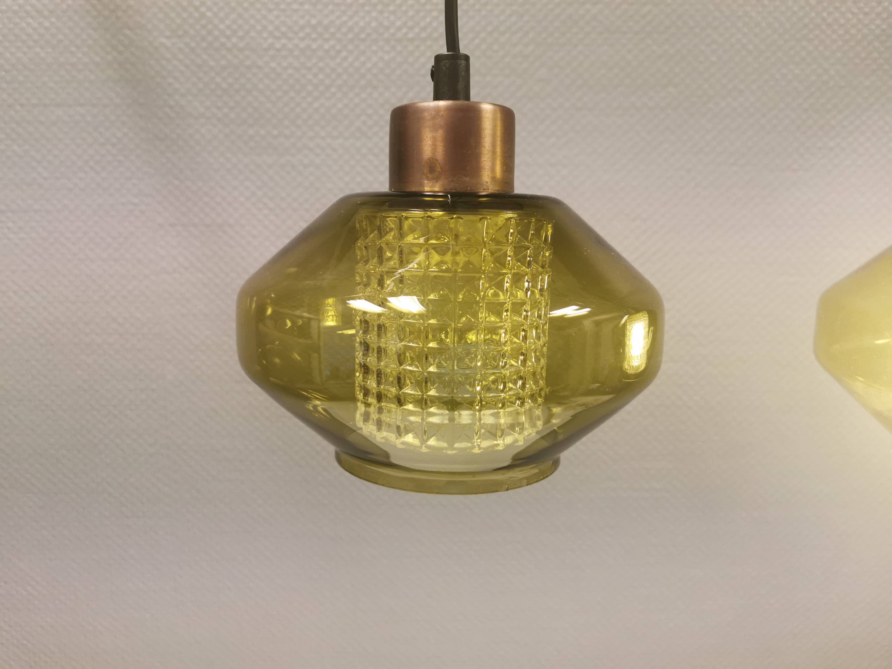 Hanging lamp with an outer shade of olive green glass and an inner shade of clear, crystal glass.