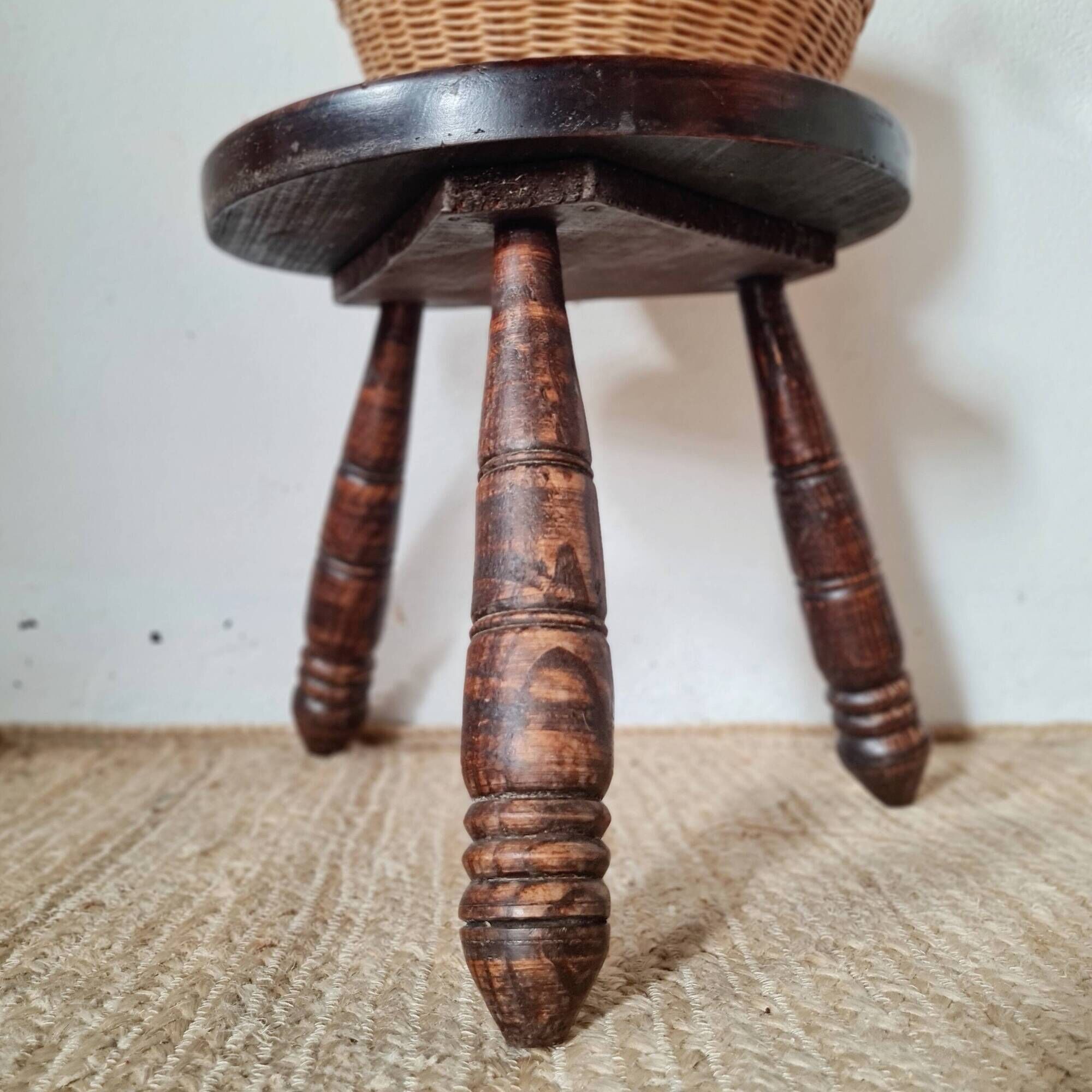 Small brutalist tripod stool made of turned wood.