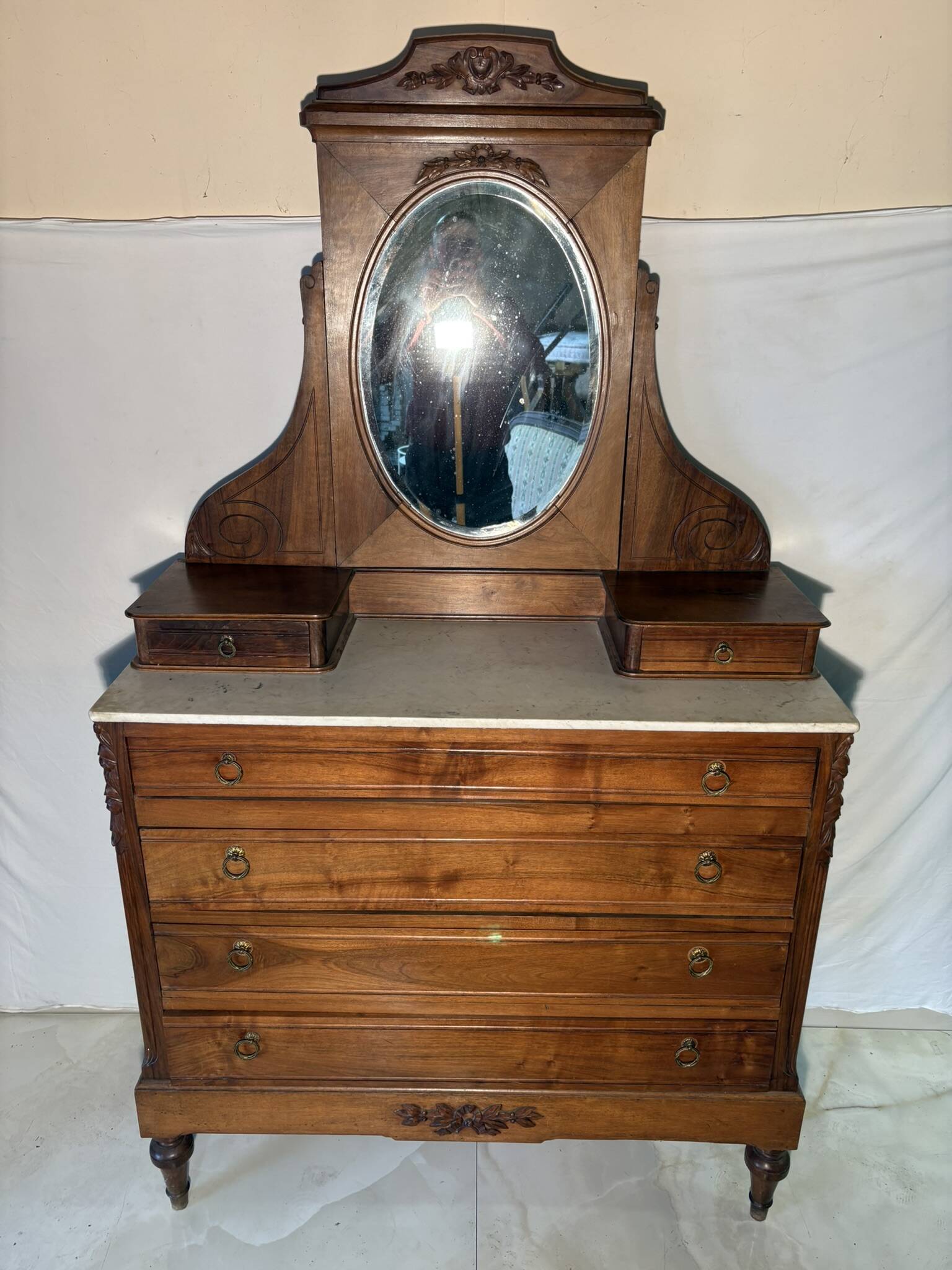 Antique carved wooden dressing table with marble and tilting oval mirror.