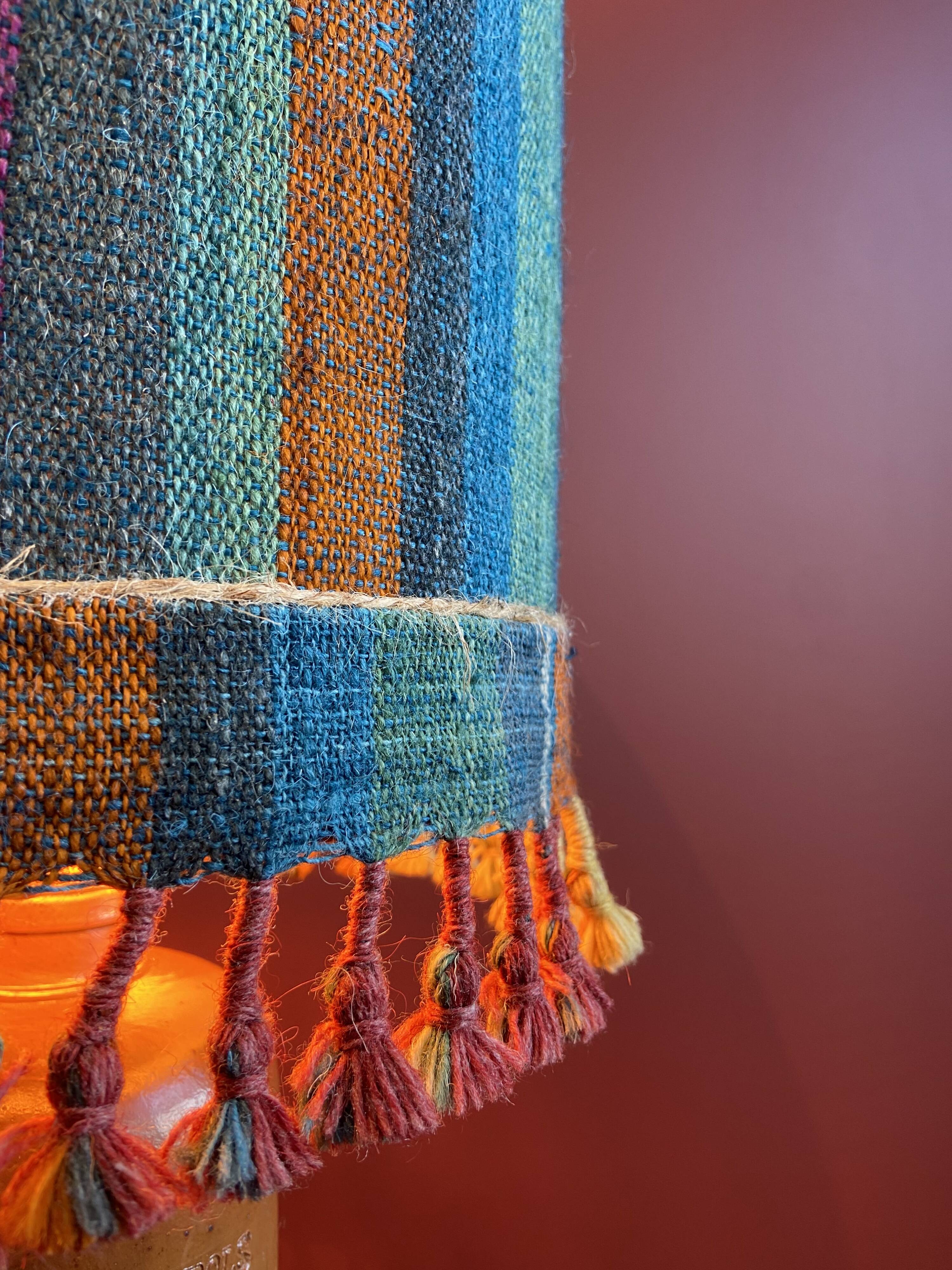 "Stoneware Bottle Lamp" with a multicoloured blue lampshade handwoven in India.