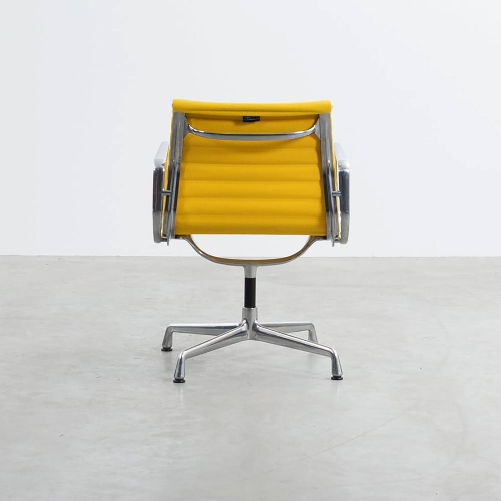 Fauteuil Aluminum Group EA107 de Charles et Ray Eames en tissu jaune.