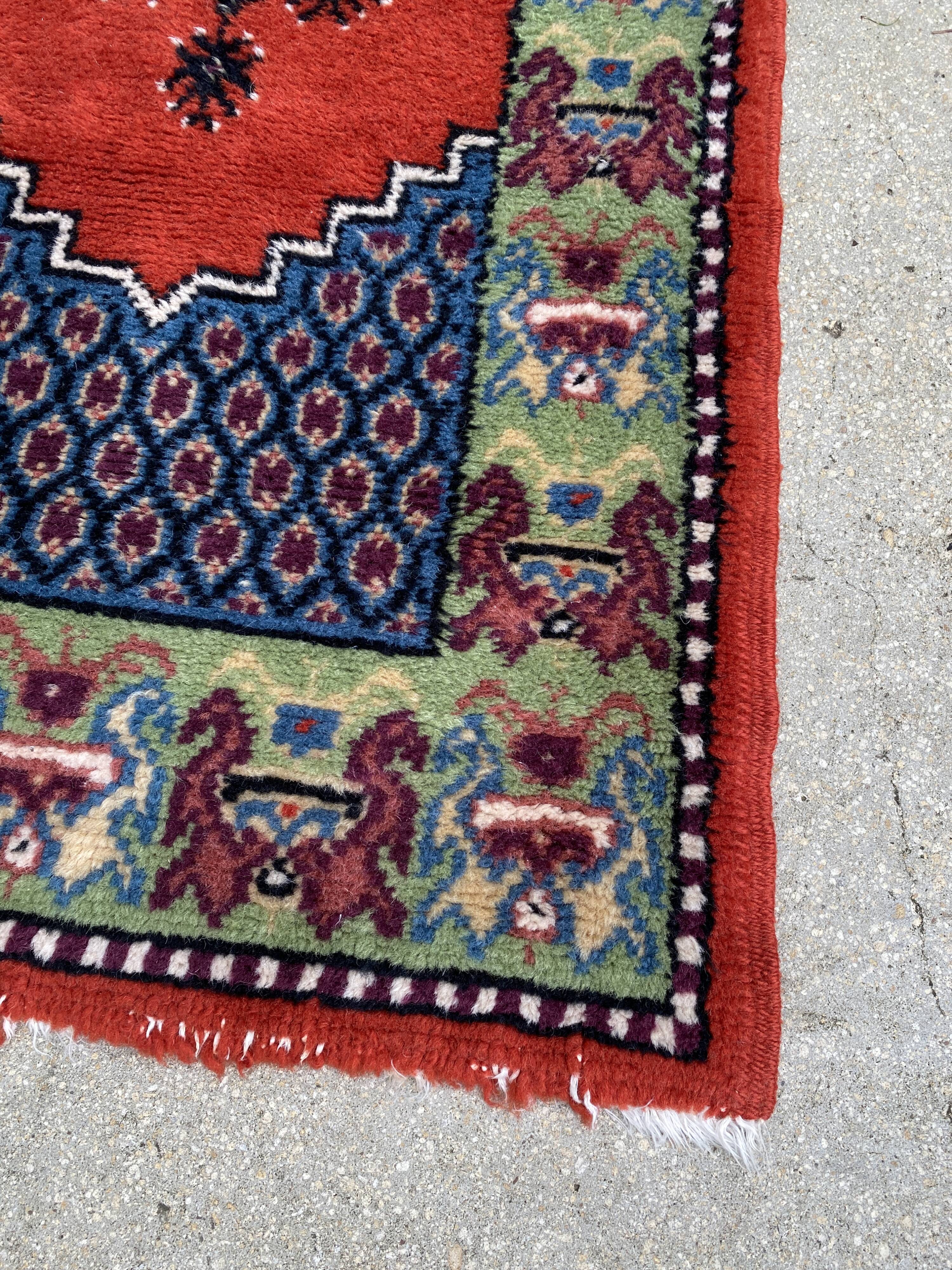Vintage hand-knotted wool rug with polychrome decoration on a red, blue, green background 150 x 63 cm